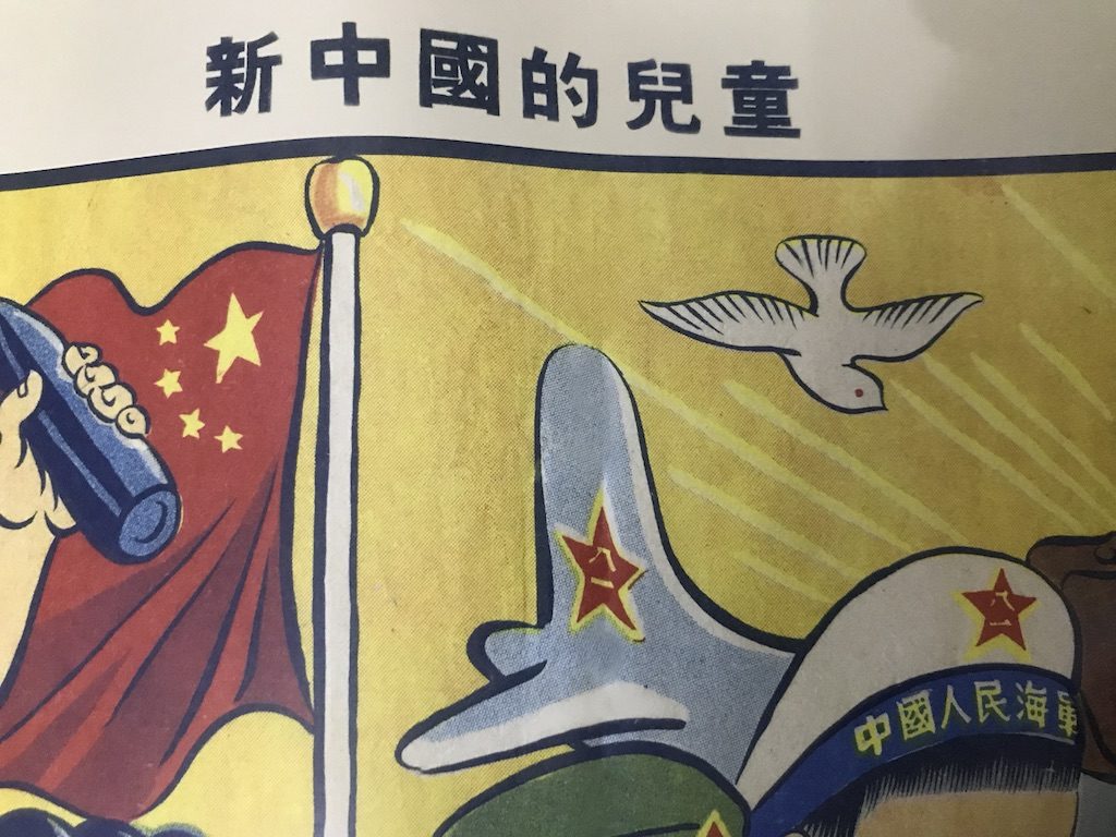 Chinese characters on a propaganda poster. You can see a flag and the end of an airplane and a hat.