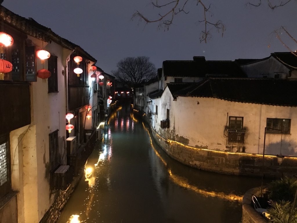 a canal in Suzhou, lit up in the evening.