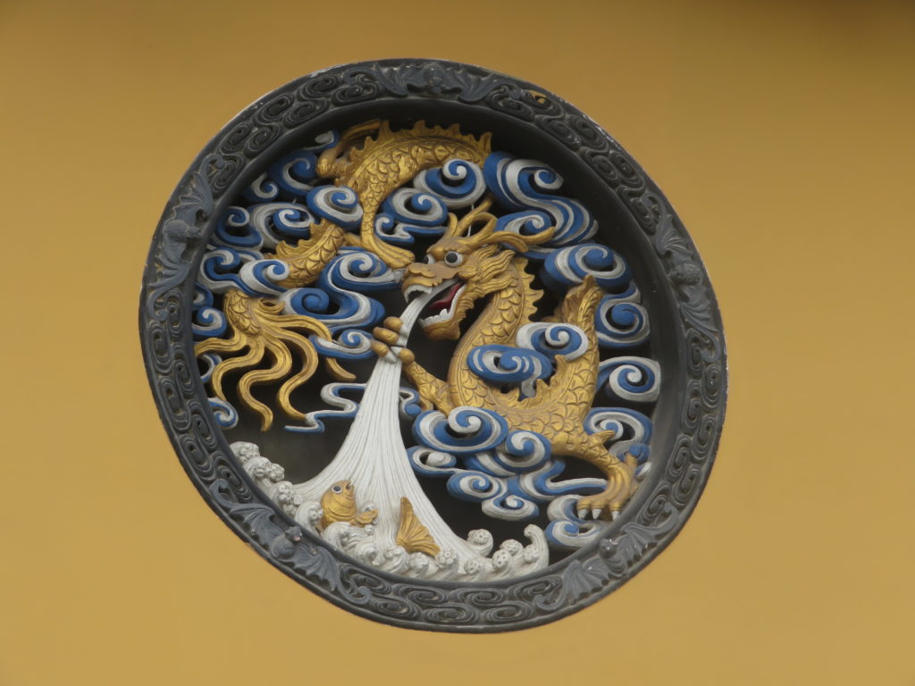 a carved chinese dragon in a yellow wall