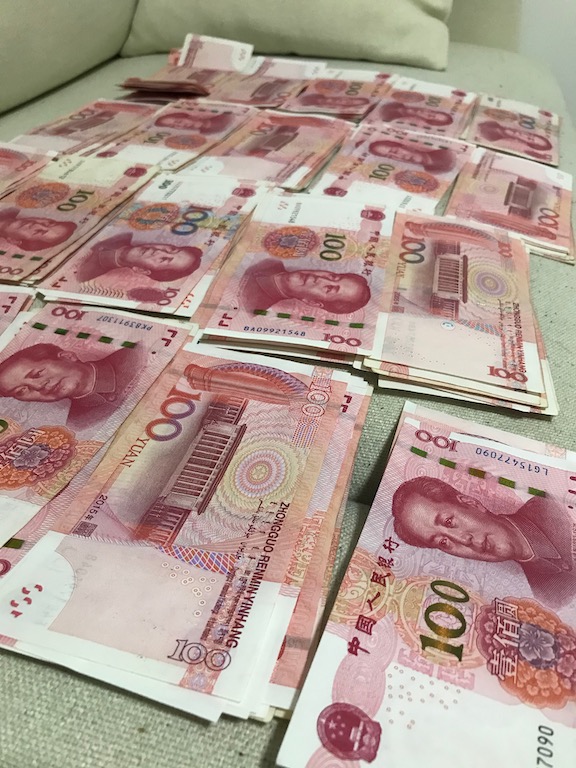 piles of Chinese RMB - how to save money for travel a working class guide - onaroadtonowhere.com
