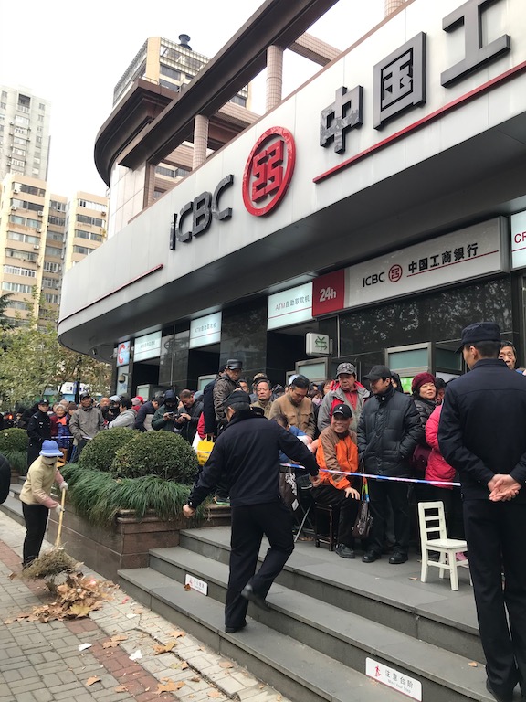people line up outside a Chinese bank - how to save money for travel a working class guide - onaroadtonowhere.com