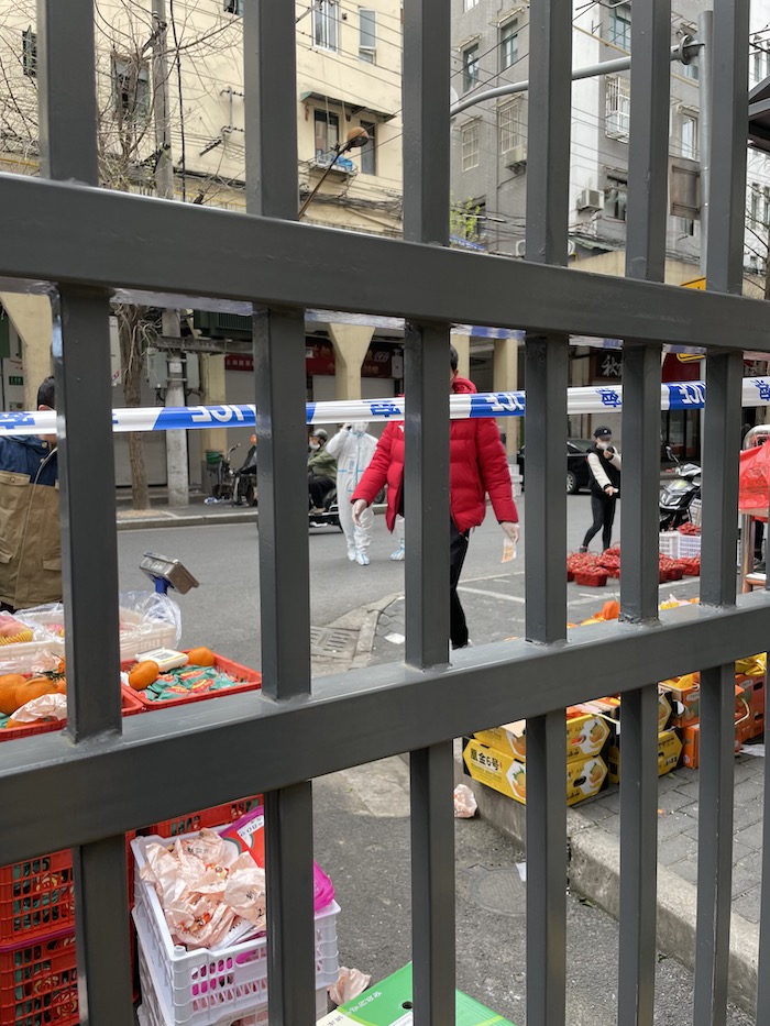 Vendors selling fruit through a gate during Shanghai's lockdown - onaroadtonowhere.com