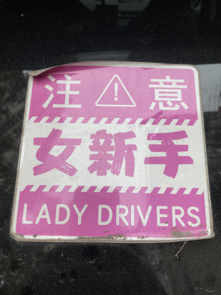 A car sign says 'be careful, woman driver' in Chinese