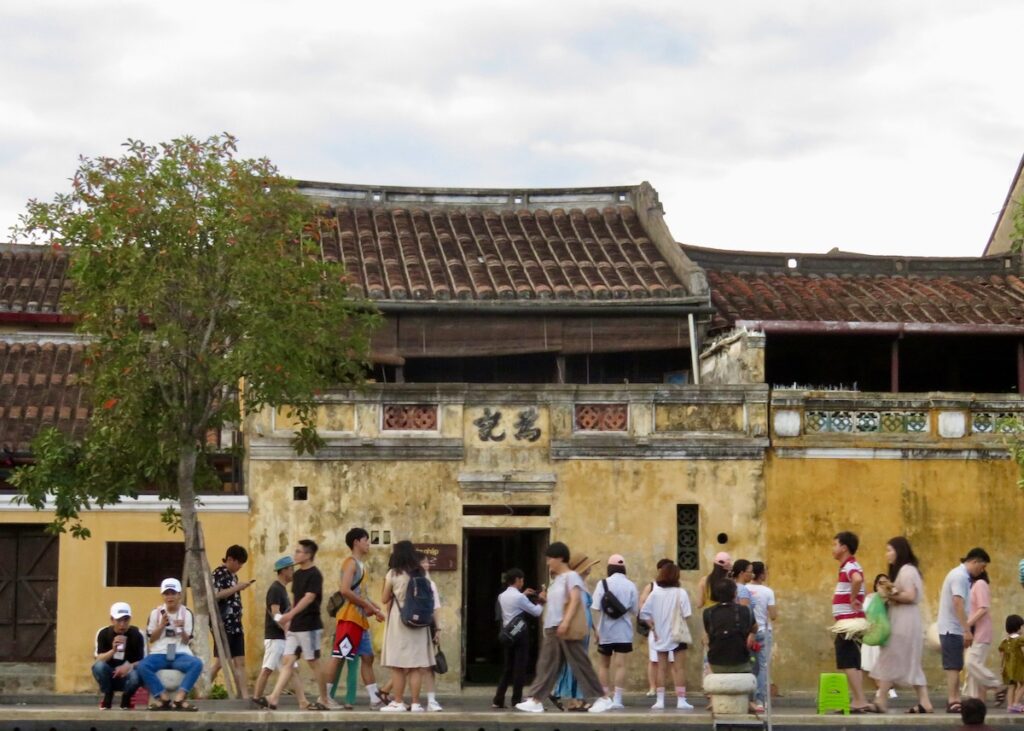 a crowd walks down the street in Hoi An ancient town - onaroadtonowhere.com