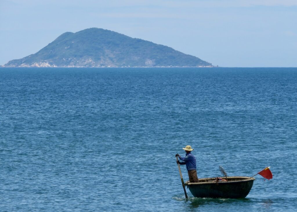 Man in traditional wicker boat on the ocean in Vietnam -onaroadtonowhere.com