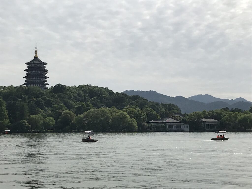 Boats float in the lake in front of a Chinese Pagoda in West Lake, Hangzhou, China.