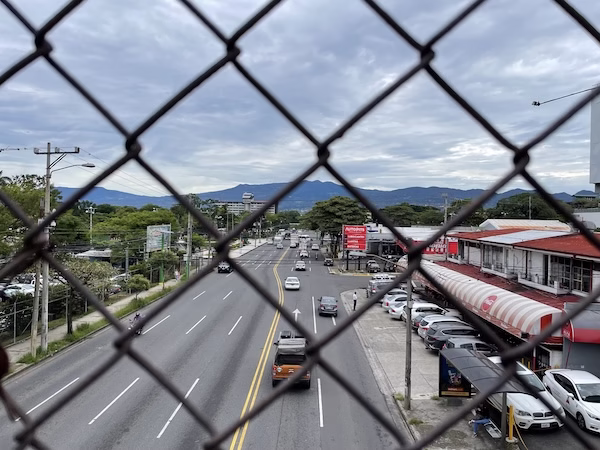 A street behind a chain link fence in Central America