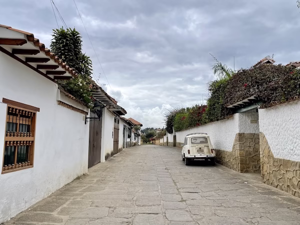 An old car parked on a cobblestone street in front of colonial houses in Villa de Leyva