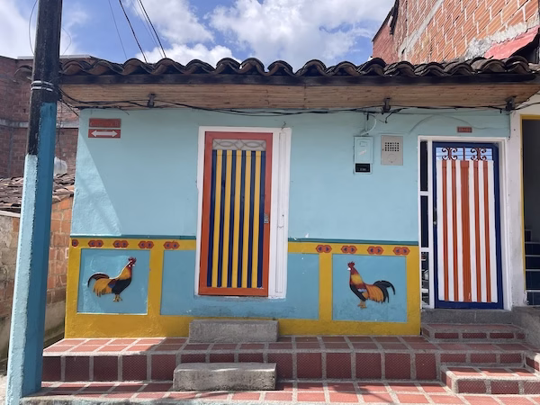 Zócalos in the shape of a rooster on a bright yellow and blue Colombian house