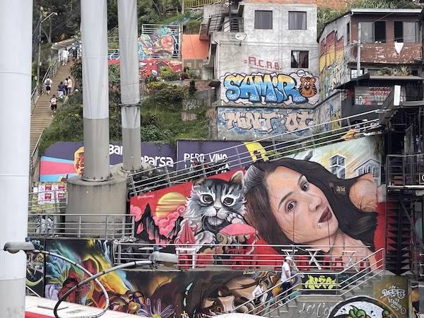 Graffiti showing a woman and a grey cat on a wall near a staircase