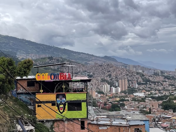 A colorful bar that says "Colombia" in front of the skyline of Medellín from a hillside.