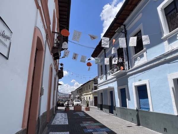 Halloween decorations hang over a cobblestone street in the San Blas neighborhood of Quito