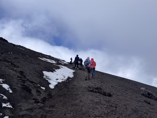 Hikers climb up the slope of Cotopaxi Volcano