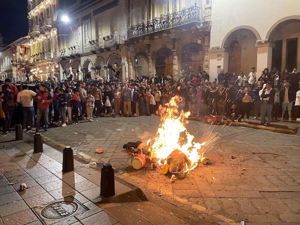 A crowd watches as effigies are burned in the street during an Ecuadorian New Year's Eve celebration