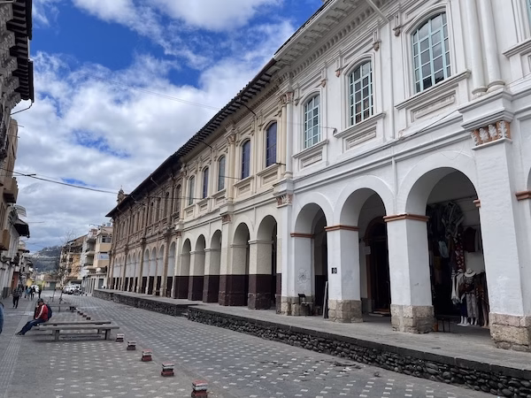 Arched buildings line a cobblestone street in Cuenca, Ecuador