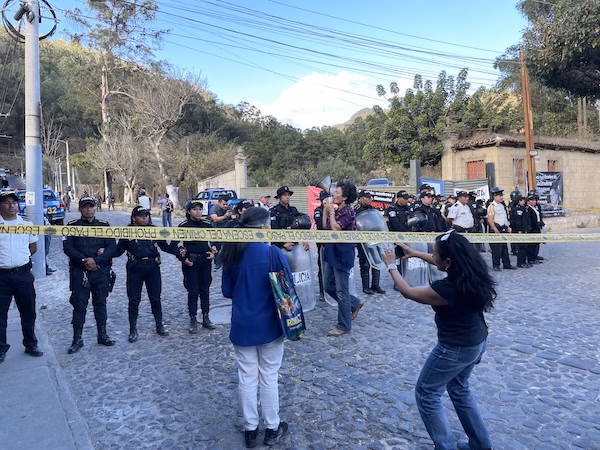 Police look on as protesters speak against the government in Antigua, Guatemala