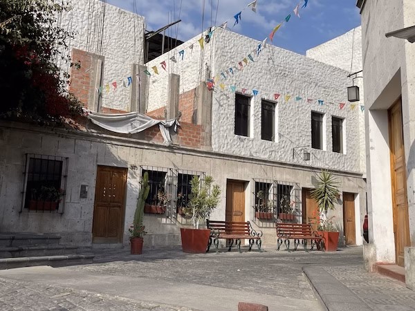 Benches on a cobble stone street in front of white stucco building in Areqiupa, Peru