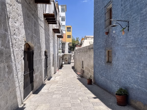 A narrow stone alleyway passes between Spanish colonial buildings