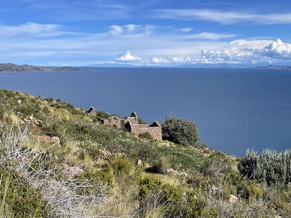 Inca buildings overlook blue water of Lake Titicaca in Peru