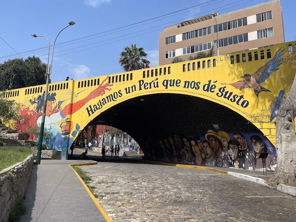A painted yellow bridge in Lima reads "hagamos un Peru que nos de gusto" which roughly translates to "let's make a Peru that gives us joy"