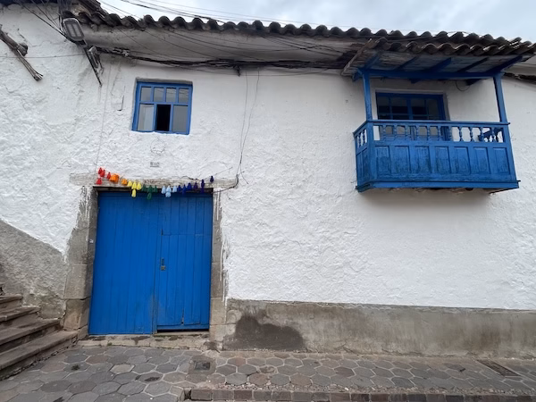 A Spanish colonial building with white walls and a blue door and small balcony.