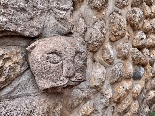 The face of a puma carved into a restored Inca stone wall