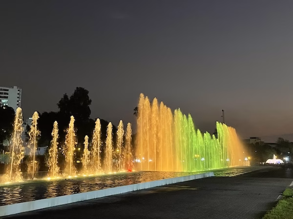 Fountains of water shooting up into the air lit by yellow and green lights as part of the Magic Water Circuit in Lima, Peru