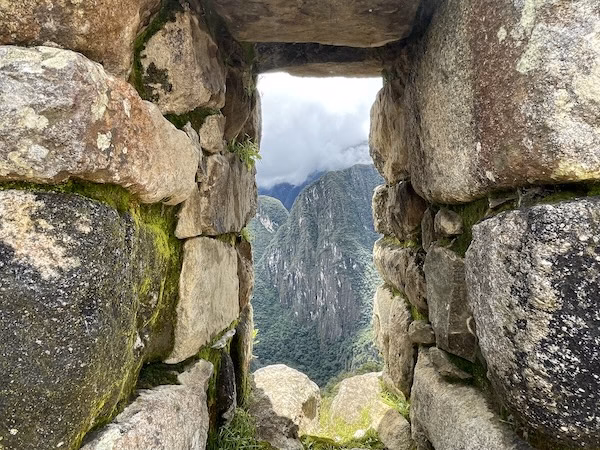 A rock window looking out at the mountains in Machu Picchu, Peru