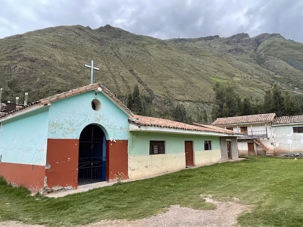 A small painted church in front of a hill in Calca, Peru