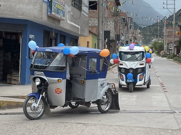 Mototaxis (tuk-tuks) with balloons drive on the street of the Valle Sagrado in Peru