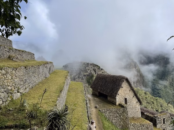 Mist slides over terraced fields and thatch roofed huts at Machu Picchu