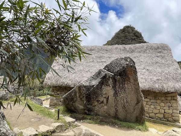 A large stone in front of a hut.