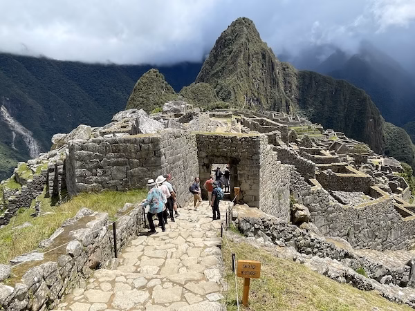 Tourists walk down a stone path in the ruins of Machu Picchu