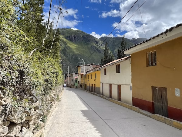 Colorful Spanish style buildings next to a rock wall in Ollantaytambo, Peru