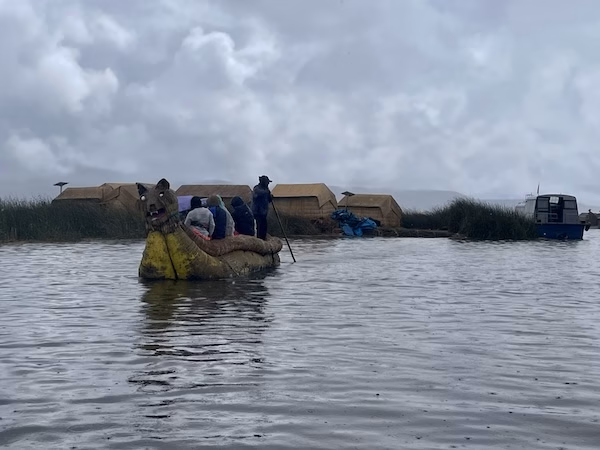 A man and tourists on a reed boat in the Uros Islands